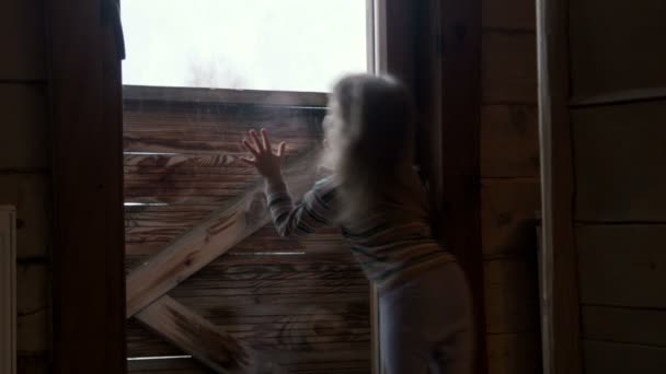 Маленькая милая девочка за окном зимой — стоковое видео