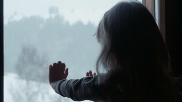 Niña linda detrás de la ventana en invierno — Vídeos de Stock