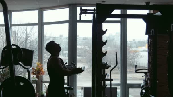 Silhouette eines männlichen Bodybuilders, der in einem Fitnessstudio hochzieht — Stockvideo