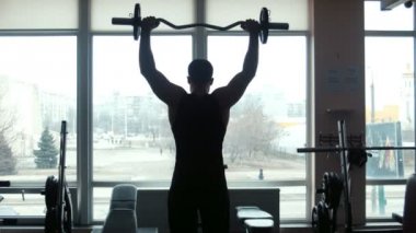 Adam halterci bir spor salonunda bir halter kaldırıyor