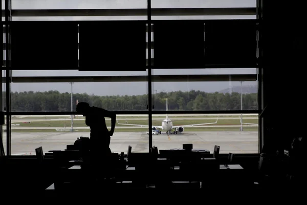 Silueta mujer esperando avión en el salón del aeropuerto — Foto de Stock