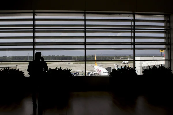 Silueta hombre hablando por teléfono en el salón del aeropuerto a la espera de avión — Foto de Stock