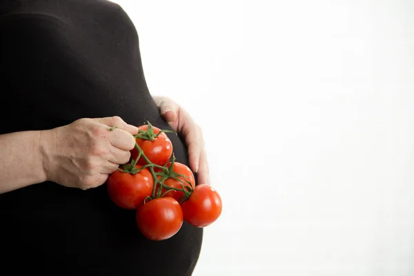 Embarazada sosteniendo tomates en la mano, comida sana aislada sobre fondo blanco — Foto de Stock