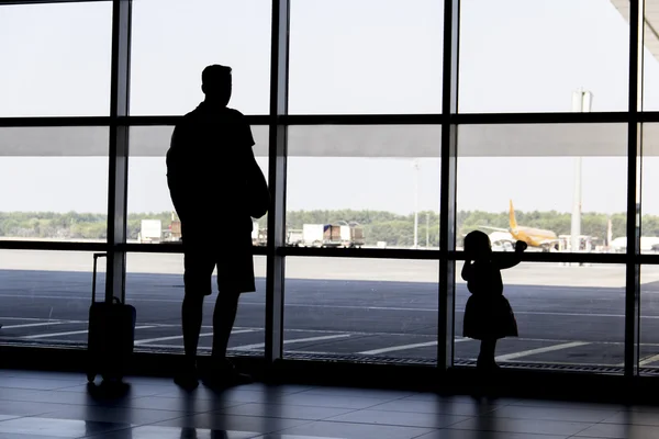 Silhueta homem e menina procurando aviões pousando no aeroporto — Fotografia de Stock