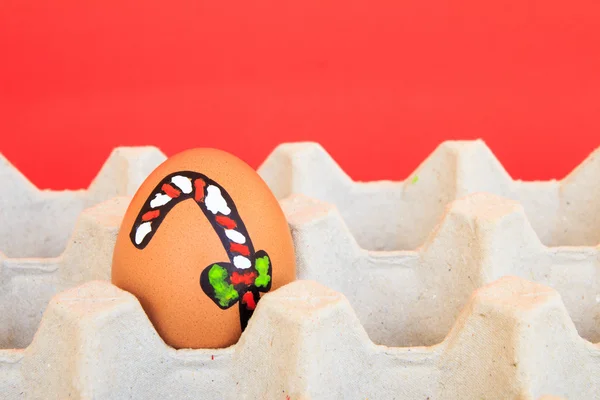 Christmas egg with faces drawn arranged in carton on red backgro — Stock Photo, Image