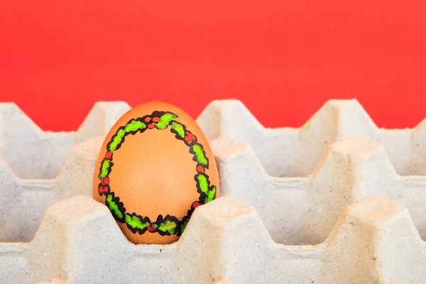 Christmas egg with faces drawn arranged in carton on red backgro