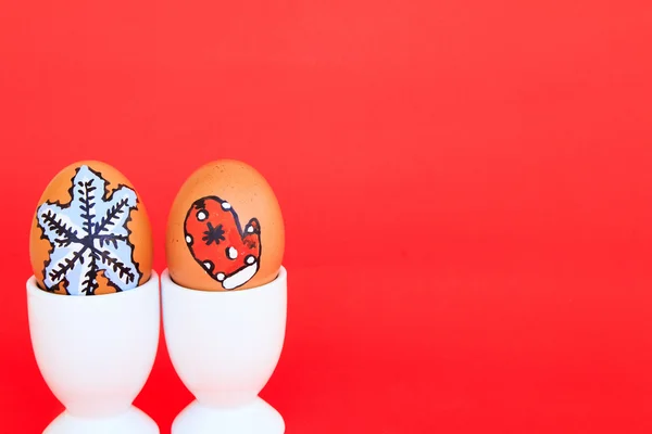 Christmas egg with faces drawn arranged in cup egg on red backgr