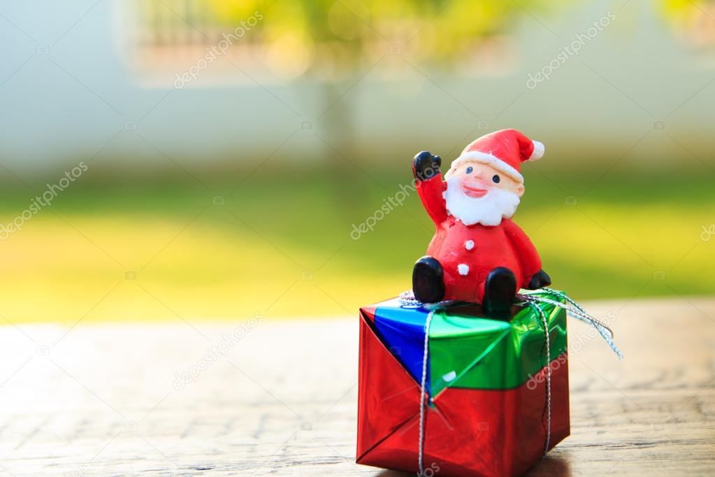 Santa Claus with gift on wood table ,in garden background