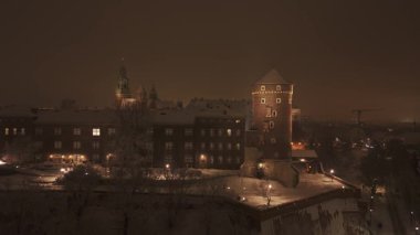 Karlı Wawel Kalesi 'nin etrafında parlayan ışıklarıyla akşam uçuşları..