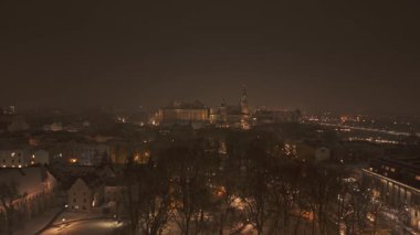 Wawel Kalesi 'nin akşam manzarası karla kaplı parlayan ışıklarla.