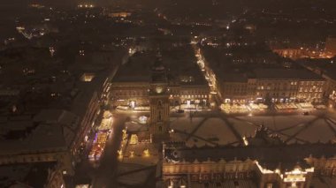 Pazar Meydanı 'ndaki çan kulesinin etrafında St. Marys Kilisesi, kar ve ışıklarla akşam uçuşu..