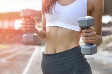 Dışarda poz veren cılız bir kadın. Egzersiz yapıyor ve spor takım elbise giyiyor.