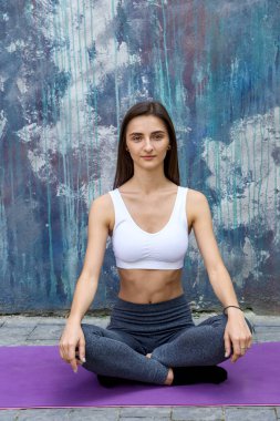 Sabah egzersizleri dışarıda. Genç bir kadın şehirde paspasın üzerinde antrenman yapıyor.