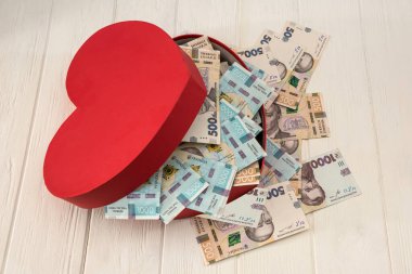 Para dolu kırmızı kalp şeklinde bir kutu. UAH Ukrayna 'nın parası 1000 ve 500 banknot masaüstünde