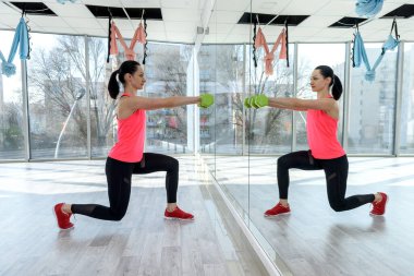 Spor salonunda halterli kadın eğitimi.