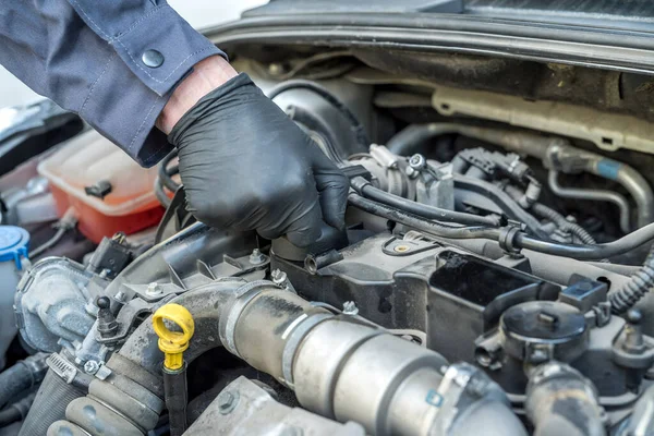 mechanic is opening the oil cap for change of oil from a car engine. auto service