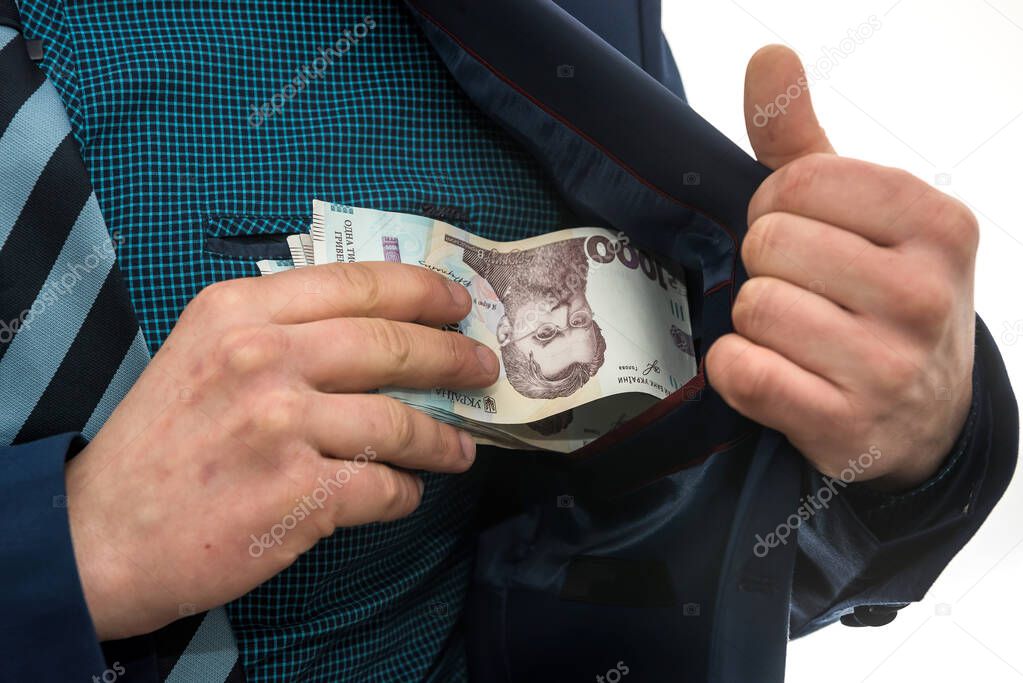 businessman takes a pack of Ukrainian money as a bribe and hides in his pocket in a jacket. Corruption and a trick. UAH. 1000 new banknote