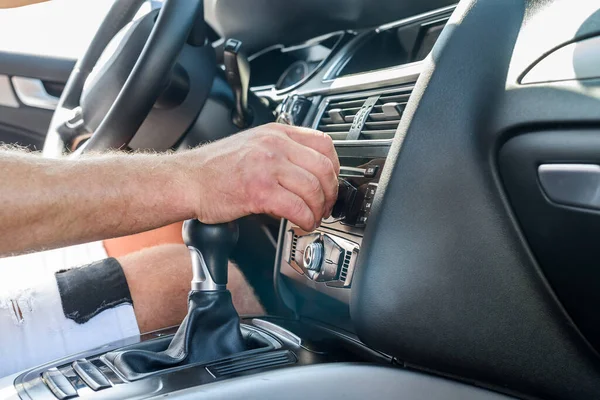 Male hand on transmission gear inside car. Close view of male hand with car interior