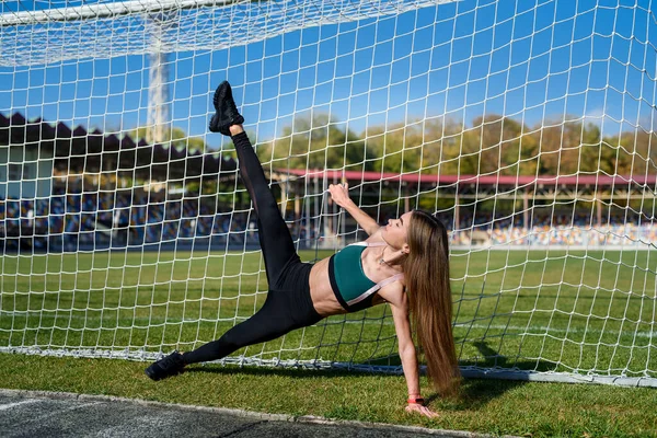 完璧な姿の美しい女の子がスタジアムのサッカーのゴールの近くに立っています フィットネスと健康的なライフスタイルのコンセプト — ストック写真