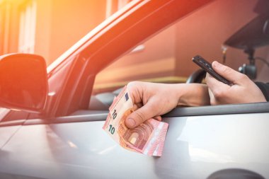 Adam, park ücretini ödemek için arabadayken avro sayıyor. Yolculuk konsepti