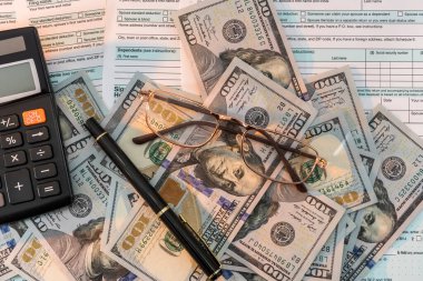 Masada 1040 vergi formu, kalem hesap makinesi ve dolar var. iş kavramı.