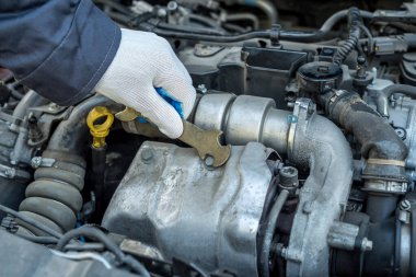 Garajdaki tamircinin elinde İngiliz anahtarı ve araba tamir aleti var. otomotiv tamiri