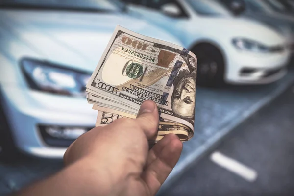 男人拿着100美元的钞票去买或租一辆新车 销售新汽车概念 — 图库照片