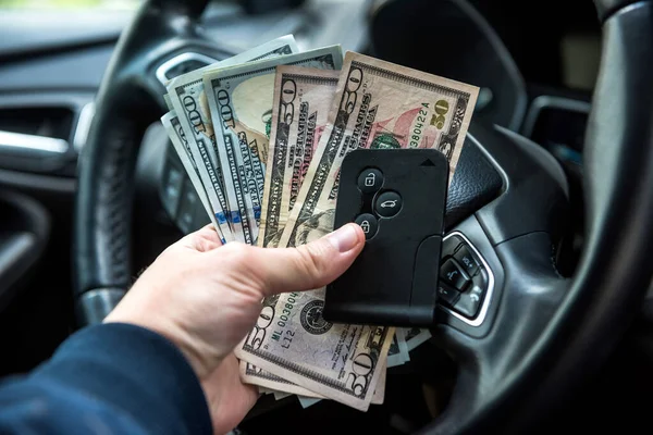男性の手はドルと車のキーを持って車の中に座っている 金融の概念 — ストック写真