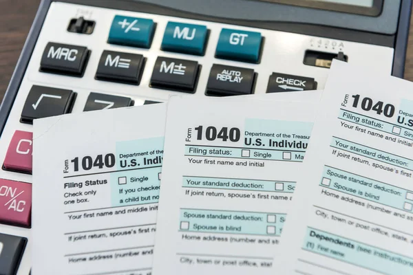 Tax concept 1040 tax form with calculator on desk. Finance time