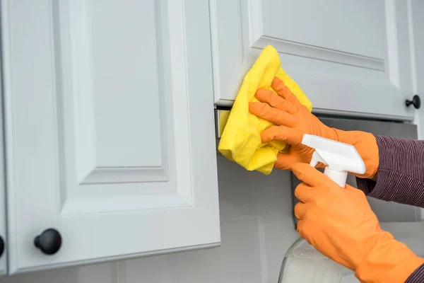 male hands in protective gloves cleaning the kitchen hood with rag and spray bottle . housekeeper