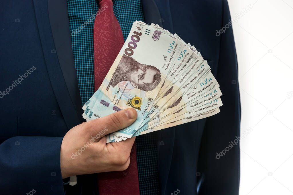 A man in a suit with a huge pile of Ukrainian money. 1000 hryvnia. UAH.