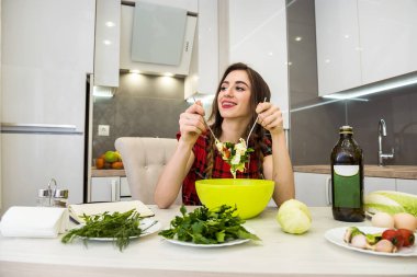 Sağlıklı bir yaşam için mutfakta sebze salatası yiyen bir kız.