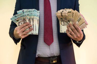 Takım elbiseli bir adam büyük miktarda Ukrayna parası tutuyor ve gelirini gösteriyor. - Evet. Yeni banknotlar 1000 ve 500 Hryvnia