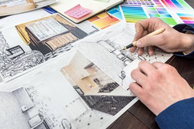 Genç tasarımcı modern bir apartman dairesi seçimi ve onarımı üzerinde çalışıyor. Ofisteki masada düz ve renkli desenler çiz