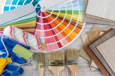 Renkli kağıt palet rehberi olarak boya aletleri, mavi eldivenler ve ahşap tahta üzerinde fırça. İnşaat ve yenileme konsepti