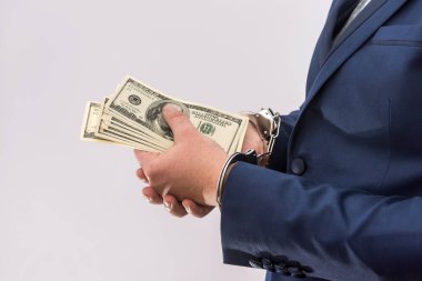 Ellerinde dolar banknotları olan kelepçeli bir adam izole edilmiş, yakın plan. Tutuklama