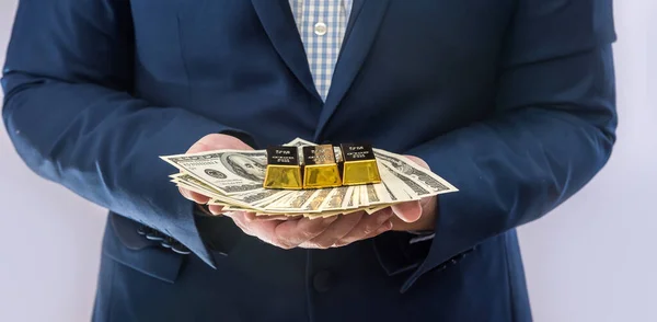 Man in suit hold money dollar bills and gold bar. Business success