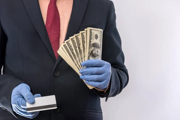 concept of security when paying for a product or service, businessman holding money and credit card in gloves. covid19 coronavirus
