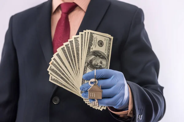 safety sale or rent house man in medical gloves hold house key and dollar. ncov2019