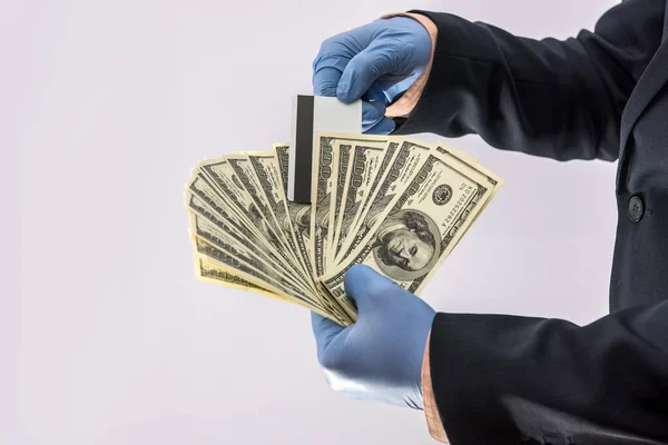 concept of security when paying for a product or service, businessman holding money and credit card in gloves. covid19 coronavirus