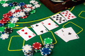 Kufr s dolary, hrací karta, pokerové žetony na zeleném pokerovém stole.