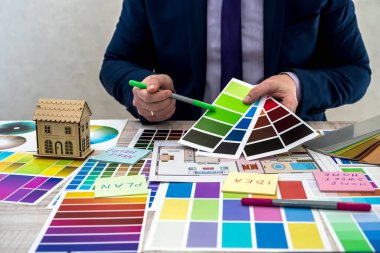 Tasarımcı, iç çizimlerin bir çizimini bir masa, ofis işyeri üzerinde renk şeması ile geliştirir. Ekipman ve malzeme örnekleriyle bir mimar ve iç tasarımcının masaüstü