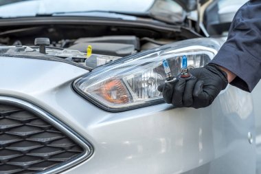 Tamirci arabanın farlarındaki halojen ampulleri değiştiriyor. otomatik teknolji