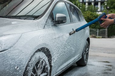 Çok zayıf bir kız arabasını köpükle yıkıyor. temizlik kavramı