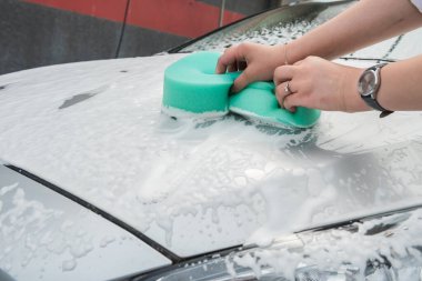Kadın arabayı sünger ve köpükle yıkıyor. Kaliteli araba servisi. Temizlik kavramı