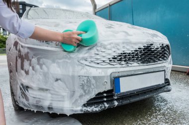 Kız arabayı köpüklü bir havluyla yıkıyor. araba temizliği