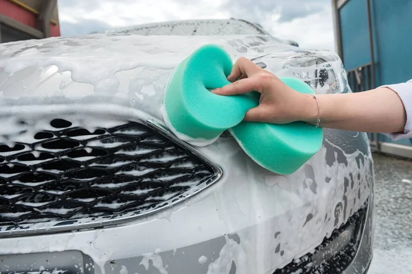 woman washes the car with a sponge and foam. quality car service. concept of cleanliness