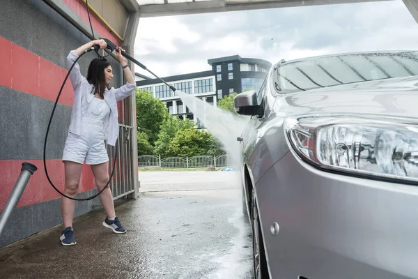 Pretty woman washing  and car cleaning with foam and pressured water. Concept for cleaning or care car.