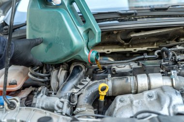 Tamirci araba motoruna yağ döküyor. Otomobil servisi. onarım