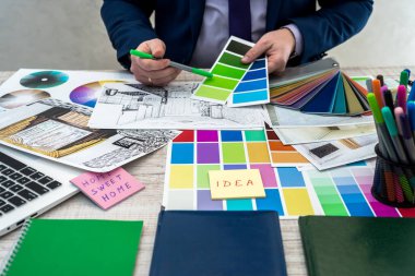 Erkek el, iç perspektife sahip renk örneklerini tutuyor. Daire çizimi, malzeme ve renk örnekleriyle çalışan iç mimar eli.